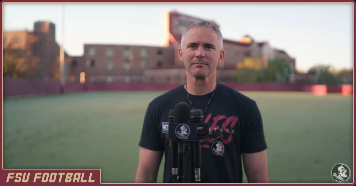 Mike Norvell standing at microphone in front of Doak Campbell stadium